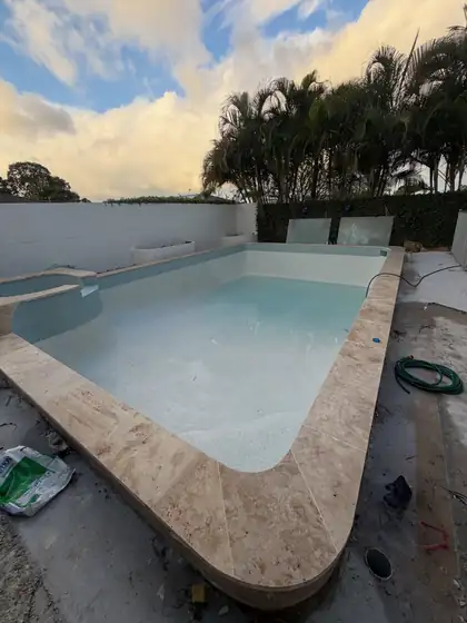 Tallai: travertine coping, porcelain waterline tiles, 50% white / 50% clear glass